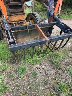 un homme debout dans l'herbe à côté d'un tracteur