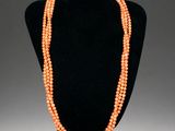an orange beaded necklace on a black mannequin
