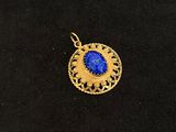 a gold plated pendant with a blue stone in the center
