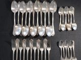 un grand nombre de cuillères et de fourchettes en argent disposées sur une table