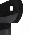 a black vase that is on a stand on a white surface