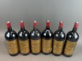 six bottles of wine are lined up in a row on a table
