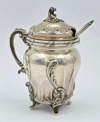 une théière ancienne en argent avec une cuillère, sur fond blanc