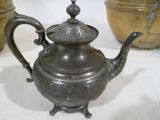 une théière en argent posée sur une table à côté de deux casseroles