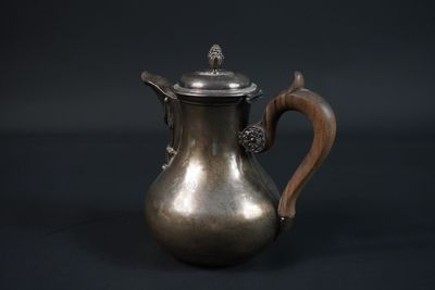 une cafetière ancienne en argent avec une poignée en bois, sur fond noir