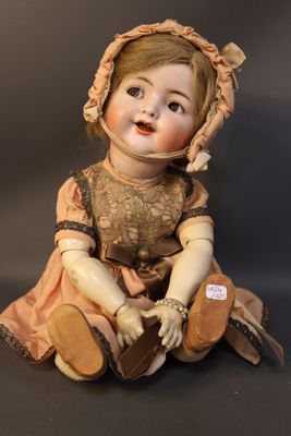 an old fashioned doll sitting on the ground wearing a bonnet and dress