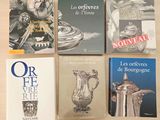 quatre livres posés sur une table sur laquelle se trouve un vase en argent