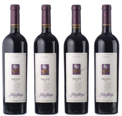 trois bouteilles de vin rouge sont alignées sur une surface blanche