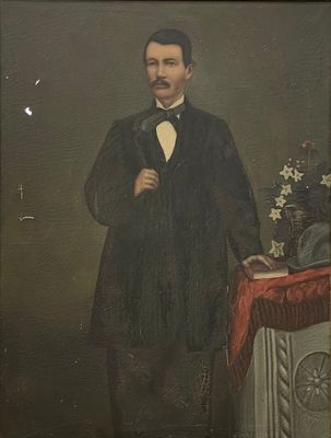 portrait d'un homme en smoking et nœud papillon, debout devant une table sur laquelle se trouve un vase de fleurs