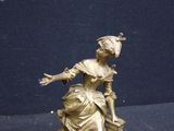 a gold statue of a woman with a basket on her lap