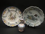 trois types d'assiettes différents et un vase posés sur un fond noir