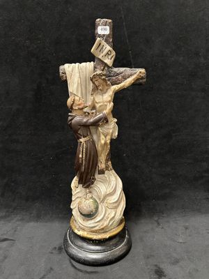 une statue représentant un homme tenant une croix, posée sur un socle