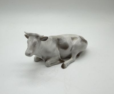 porcelain figurine of a cow laying down on a white surface