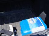the trunk of a car with a blue container of water and a pair of black gloves