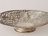 an antique silver plated bowl with handles on a stand