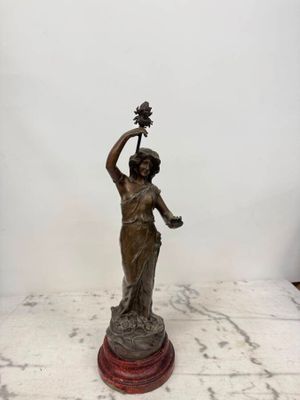 une statue de femme tenant une fleur à la main