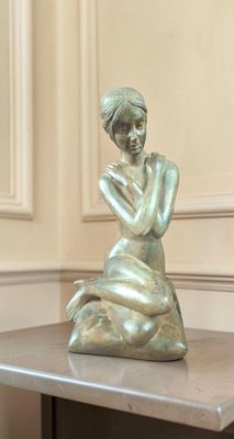 une statue de femme assise sur une table