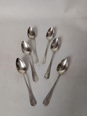 six silver spoons are arranged in a circle on a white surface