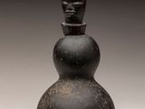 un vieux vase noir orné d'un visage sur le dessus