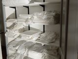 a closet filled with lots of white sheets and blankets