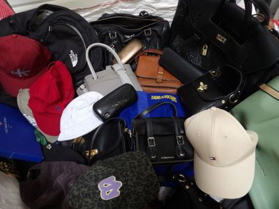 une pile de sacs à main et de chapeaux posée sur un lit