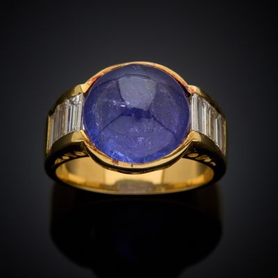 a close up of a gold ring with a blue stone and baguets