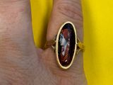 quelqu'un tient une bague sur laquelle est gravée la photo d'un homme