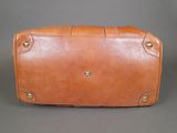 an old brown leather suitcase sitting on top of a gray surface