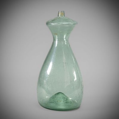 a green glass bottle with a silver top on a table