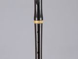 a black and gold flute with a wooden handle on a gray surface