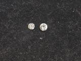 a pair of diamond earrings sitting on top of a black surface