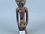 une vieille figurine en bois représentant un homme tenant une bouteille