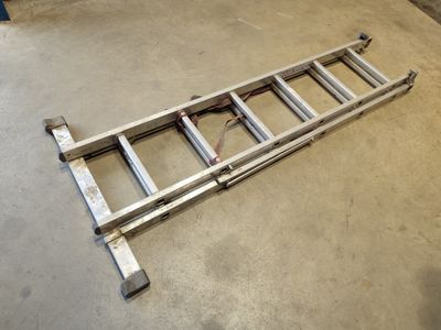 a close up of a ladder laying on the ground in a garage
