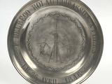 an old silver plate with a picture of a lighthouse on it