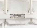 a close up of a white leather handbag with a lock