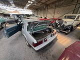 several old cars are parked in a garage with open doors
