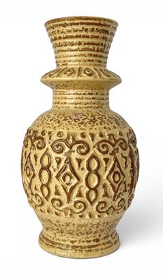 un vase jaune posé sur une surface blanche