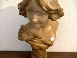 une petite statue représentant une femme aux cheveux longs, posée sur une table