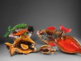 trois figurines de poissons en verre posées les unes à côté des autres sur une surface grise