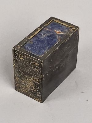 une petite boîte en métal contenant une pierre bleue