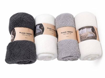 quatre rouleaux de serviettes blanches, noires et grises posés sur une surface blanche