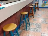brightly colored stools line the bar of a restaurant with a tiled floor
