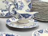many blue and white plates and cups on the table