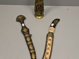 two knives and a vase sitting on a table