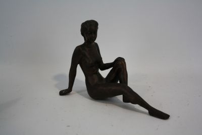 une statue représentant un homme assis sur une surface blanche