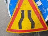 a yellow and red sign on the ground next to a white car