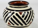 un vase noir et blanc posé sur une surface blanche