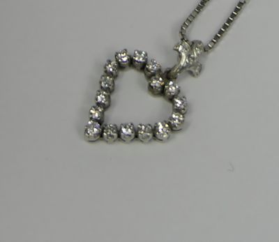 a heart shaped diamond pendant on a chain on a table
