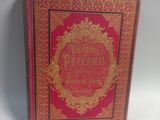 an old red book with gold writing on it sitting on a white surface
