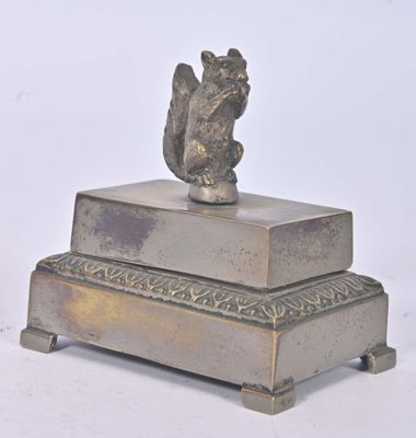 une statue représentant un écureuil posé sur une boîte